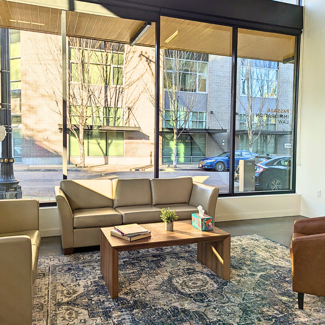 Passage Immigration's lobby including two couches, an arm chair, coffee table and some books. A cozy and inviting space. 